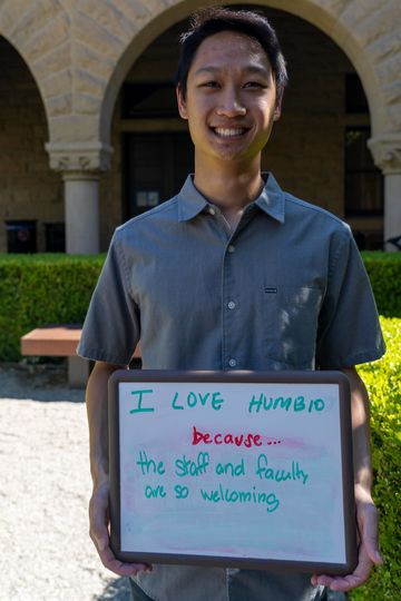 Students holds a white board that reads "I love HumBio because the staff and faculty are so welcoming"