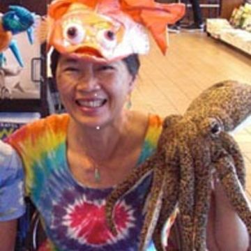 Kathleen Wong Bishop wearing a fish hat, holding an octopus stuffed animal